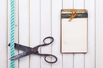 Notebook, old scissors, rope on white wood background