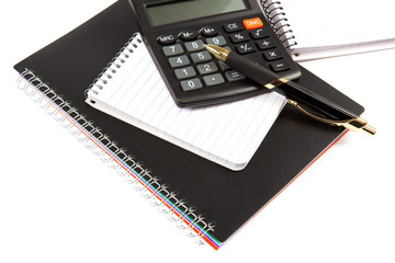 Calculator, pen and notebook on a white background.