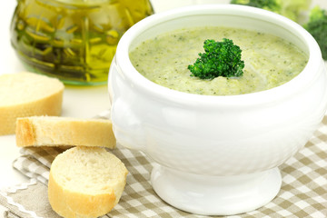 Creamy broccoli soup in a white bowl served with some bread