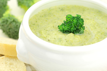 Creamy broccoli soup in a white bowl served with some bread