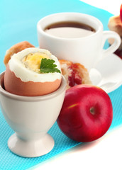 Light breakfast with boiled egg and cup of coffee, close up