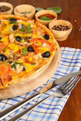 Tasty pizza with kitchen herbs on wooden table close-up