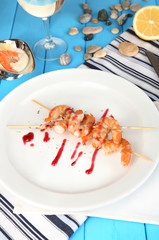 Grilled shrimp with sauce on plate on wooden table close-up