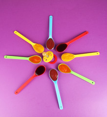 Baby puree in spoons with nipple on purple background