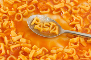 Pasta shaped letters spelling the word PASTA in tomato sauce on