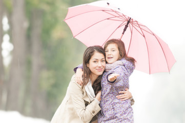 Happy mother and daughter in park in rain.