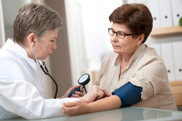 doctor measuring blood pressure of female patient