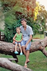 Fototapeta na wymiar Father and son have a rest on the big tree in the park