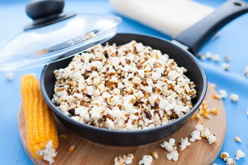 Foto op Canvas popcorn in a pan on a blue background © Olha Afanasieva