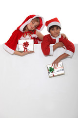 Brother and sister dressed in Santa Claus outfits