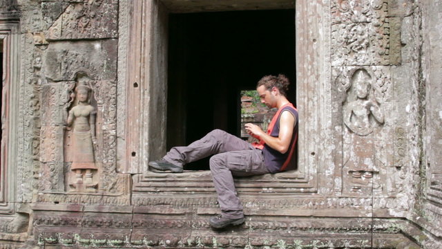 caucasian tourist using mobile phone in angkor