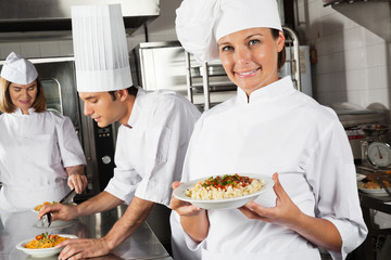 Happy Female Chef Presenting Pasta In Kitchen