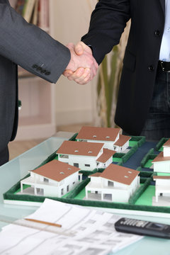 Handshake over a model housing estate