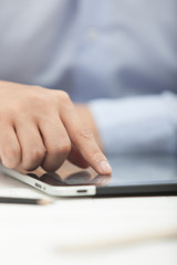 Fototapeta premium Hands of the man in the blue shirt are holding a tablet computer