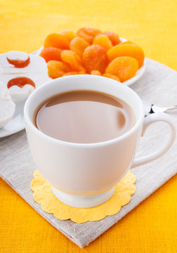 White cup of coffee with breakfast items on the orange napkin
