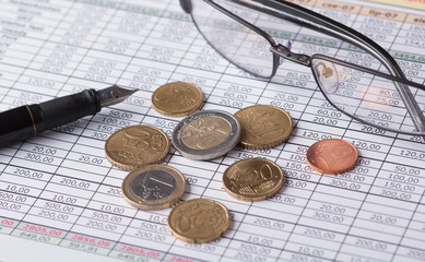 Bilon Euro leżący obok pióra i okularów na tabeli finansowej - obrazy, fototapety, plakaty