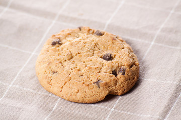 Stacked chocolate chip cookies on brown napkin.