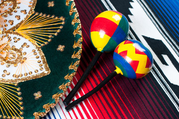 Mexican sombrero and maracas on traditional poncho, studio shot