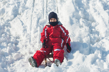Fototapeta na wymiar Kid przesuwne z sań na śniegu.