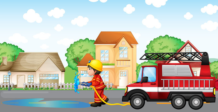 A fireman holding a hose with a fire truck at the back