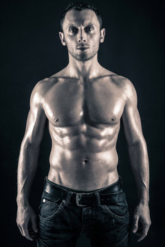 Confident young man shirtless portrait against black background.