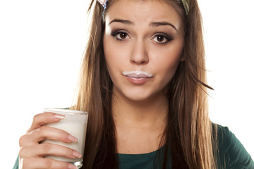 girl in a green shirt with a pleased gesture drinking milk