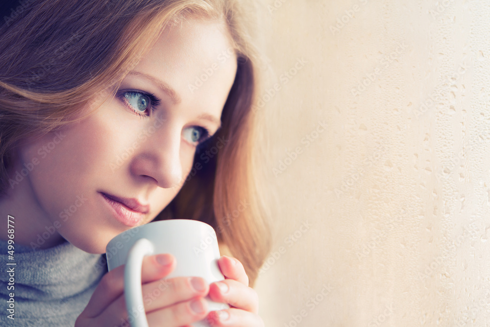 Poster beautiful dreamy girl with a cup of hot coffee at the window