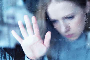 melancholy and sad girl   at the window in the rain