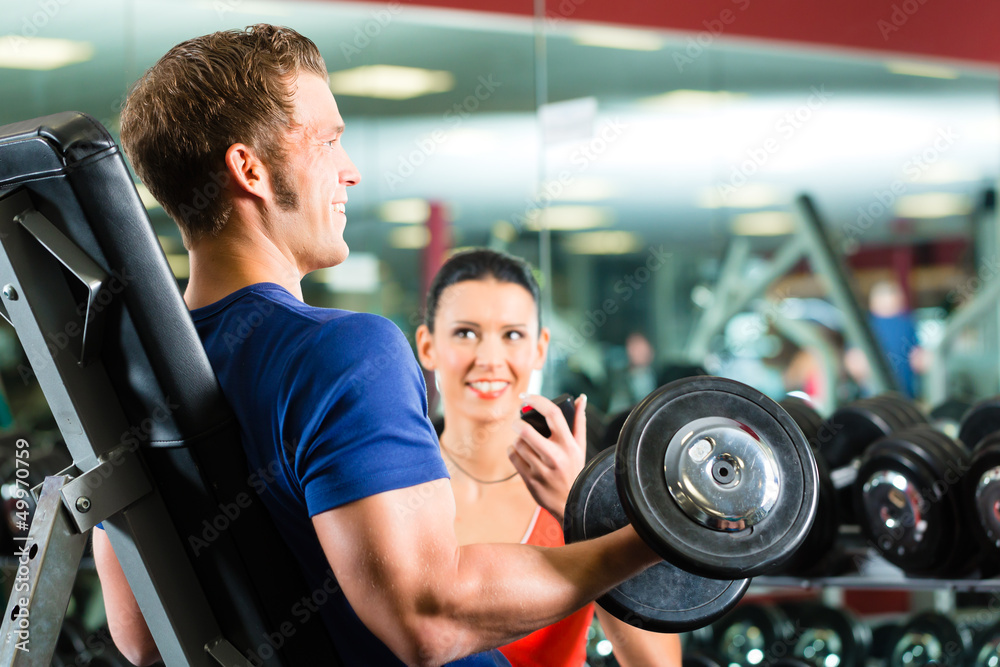 Wall mural Personal Trainer in gym and dumbbell training