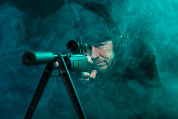 Sniper with beard in black holding gun. Studio shot.