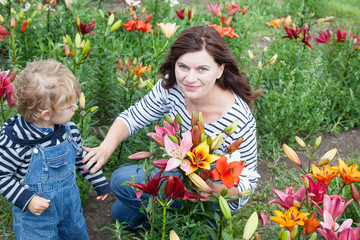 Fototapeta premium Little toddler boy and young woman on lily field in summer