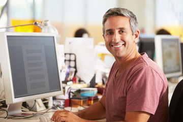 Man Working At Desk In Busy Creative Office