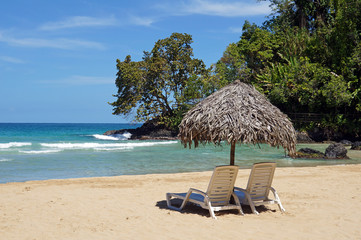 Two beach chairs with a thatched umbrella on pristine sandy beach, Central America, Panama