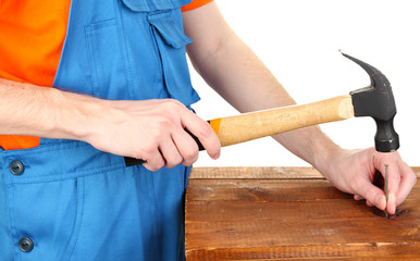 Builder hammering nails into board isolated on white