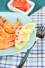 Shrimps with lemon on plate on wooden table close-up