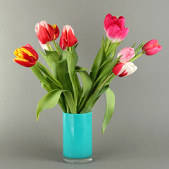 Beautiful tulips in bucket on grey background