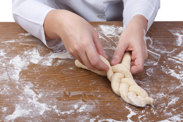 Baker's hands weave bread dough. Braiding Challah