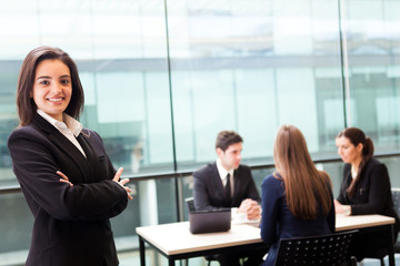 Beautiful businesswoman smiling with his colleagues behind