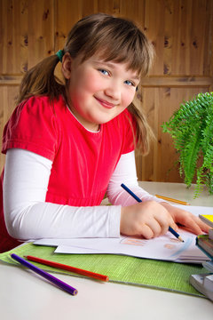 Smiling Girl Drawing At Her Desk