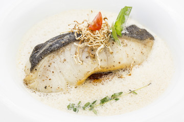 baked cod under tender sauce on a plate in a restaurant