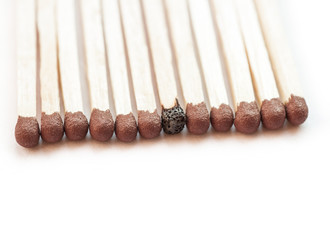 A row of matches with one burnt.