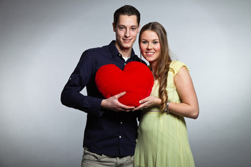 Fototapeta na wymiar Happy young romantic couple holding red heart. Studio shot.