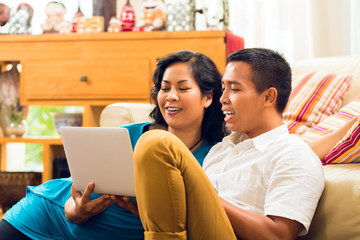 Asian people sitting in front of a notebook laughing