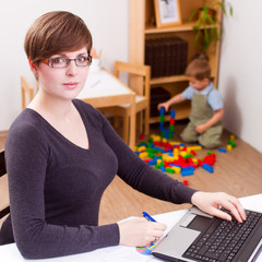 business woman working laptop her child playing at the back