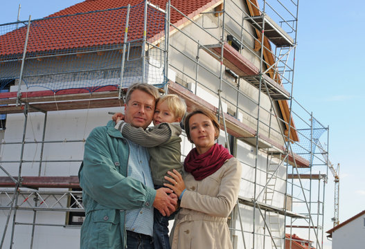 Junge Familie vor Eigenheim