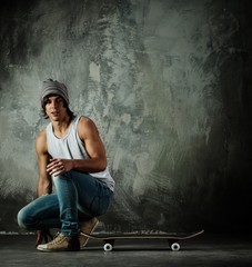 Young man in hat and jeans sitting near skateboard © Nejron Photo