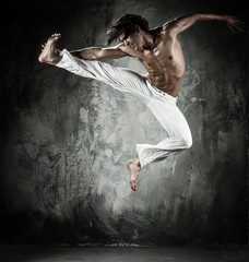 Young b-boy man with naked torso performing jumps