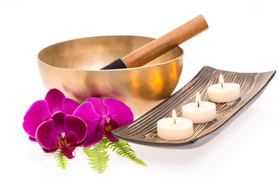 Klangschale mit Farn, Orchidee und Kerzen auf wei&szlig;em Hintergrun