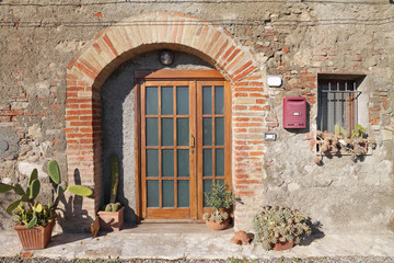 Fototapeta na wymiar przednie drzwi ozdobione roślin kaktus w toskańskim miasteczku, Włochy
