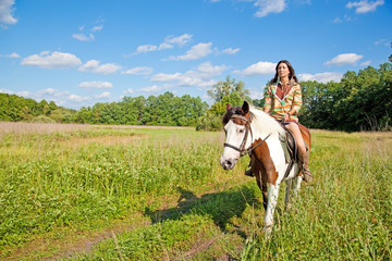 A young girl dressed as an Indian rides a paint horse